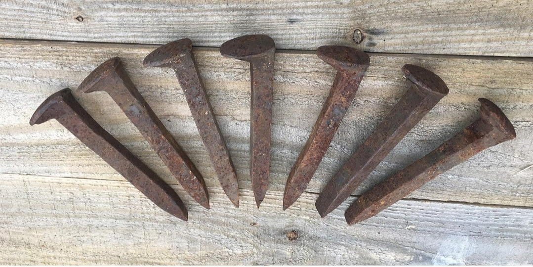 Powerful, historical railroad spikes on wood surface for protection and hoodoo practices.